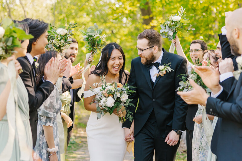 Bride and groom running through the cheering bridal party