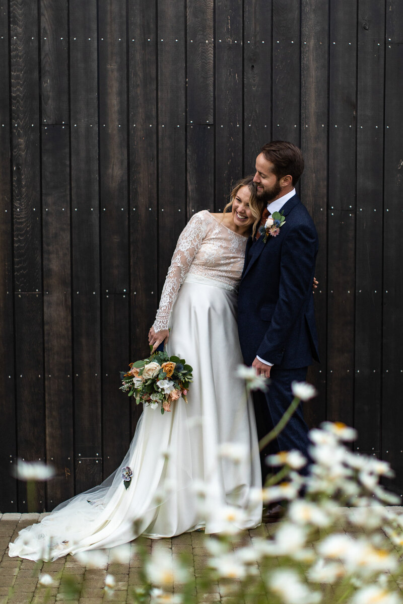 bride and groomposing in front of black shed