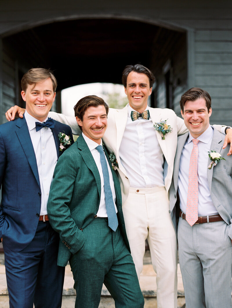 Groom smiling with his arms around groomsmen