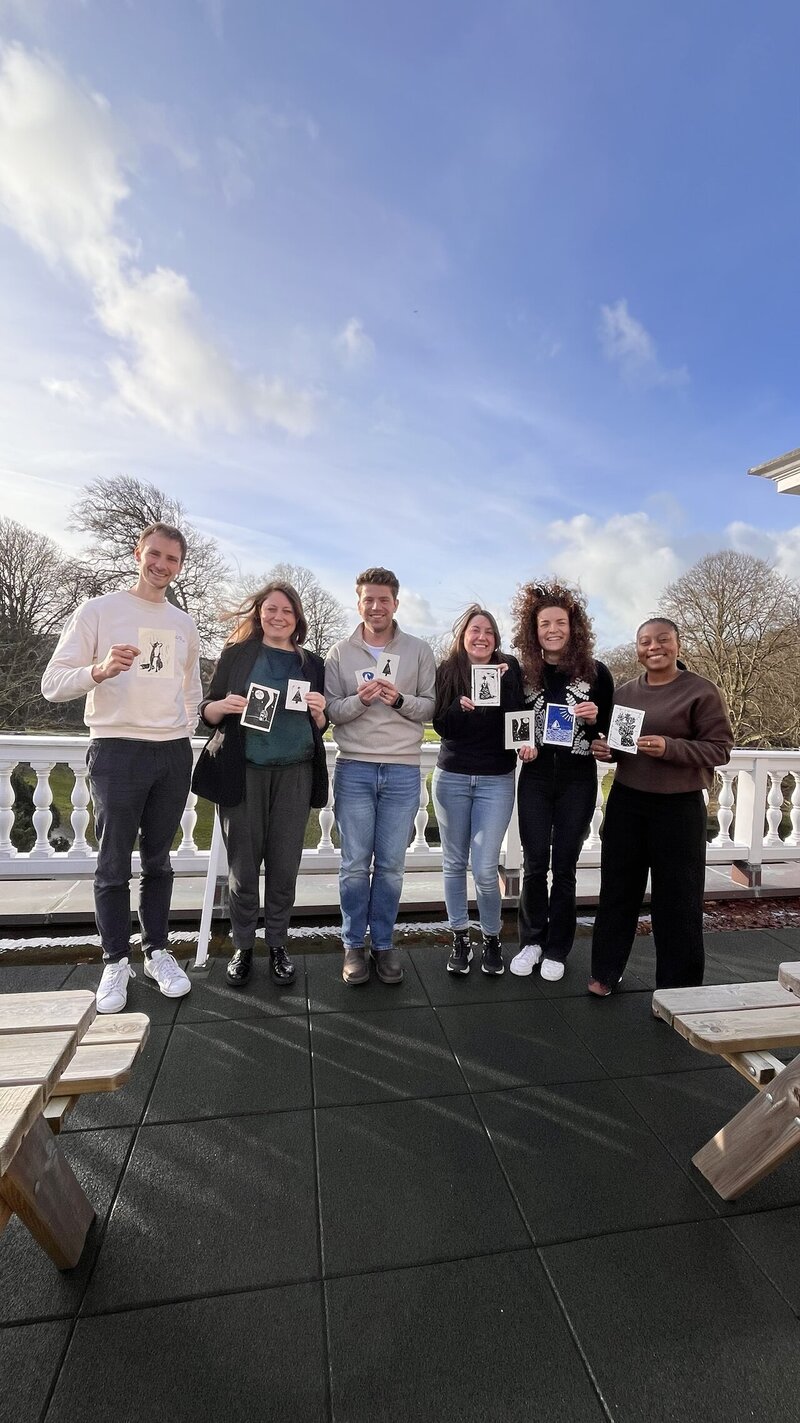 Groepsfoto van een teamuitje na een blockprint workshop met resultaten van hun werkjes