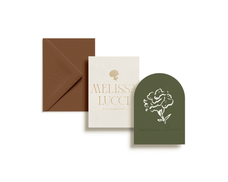 A brown envelope, a white card with "Melissa Lucci Photography" text, and a green arch-shaped card with a floral illustration and "Melissa Lucci" signature, all showcase the meticulous touch of a Showit website designer for photographers.