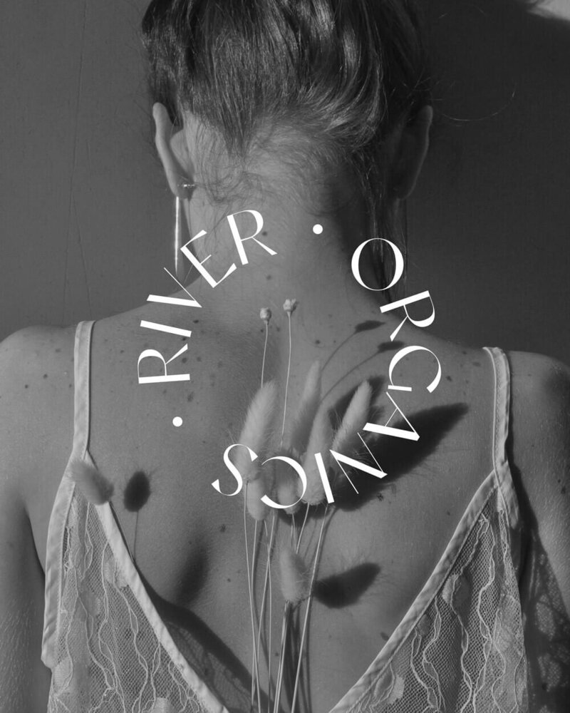 A black-and-white image of a woman’s back with water droplets, overlaid with the River Organics logo in a circular design. The imagery emphasizes purity, hydration, and the brand’s connection to nature.