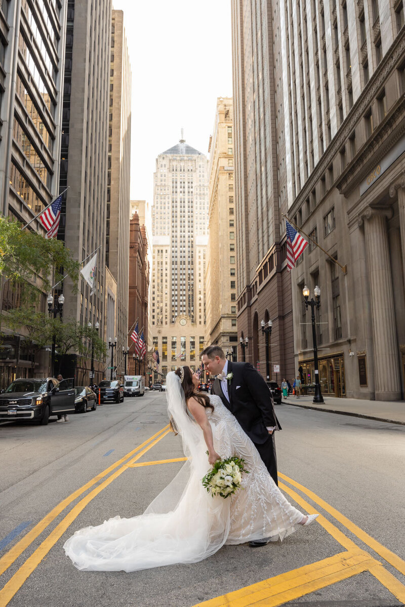A bride and groom kissing on a city street