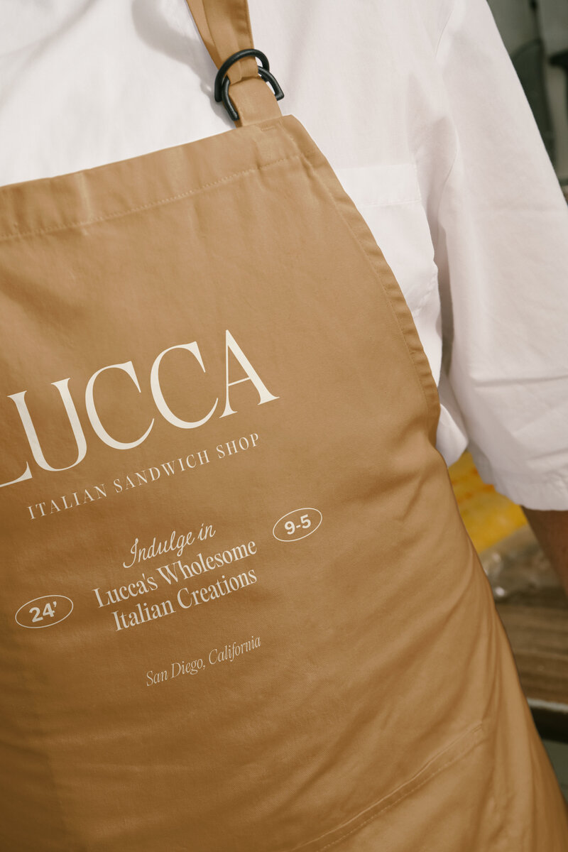 LUCCA Italian Sandwich Shop branding on tan apron, showcasing timeless brand identity and custom typography.