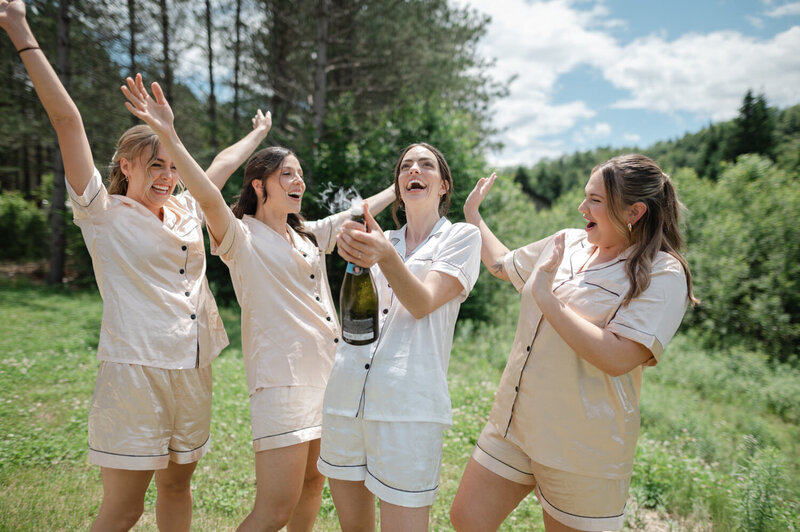 Les femmes du cortège font sauter le champagne et célèbrent avec enthousiasme cette journée grandiose à venir, dans un mariage champêtre et festif au cœur des Laurentides
