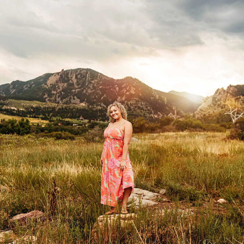 High school senior girl in a floral dress at sunset in the mountains of Boulder.