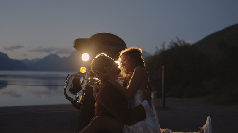 Bride and groom embracing one enother while sitting in front of motorcycle