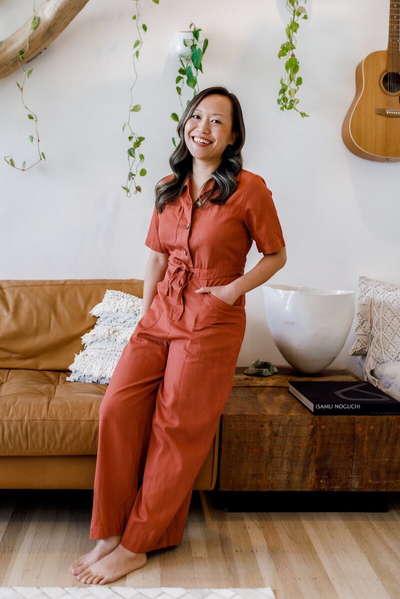 Shaochen, the owner of Monstera Gold Calligraphy Studio, in front of a leather couch and plants