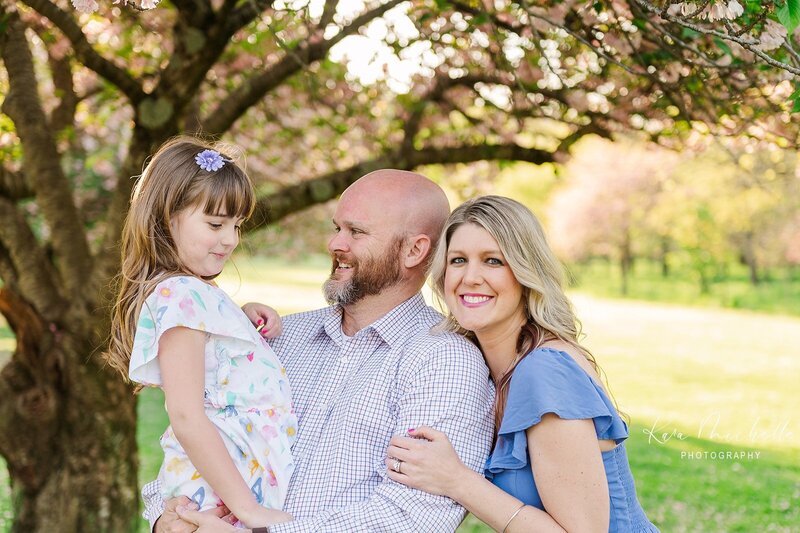 family of three posing together at lancaster central park with the cherry blossoms by york pa photographer