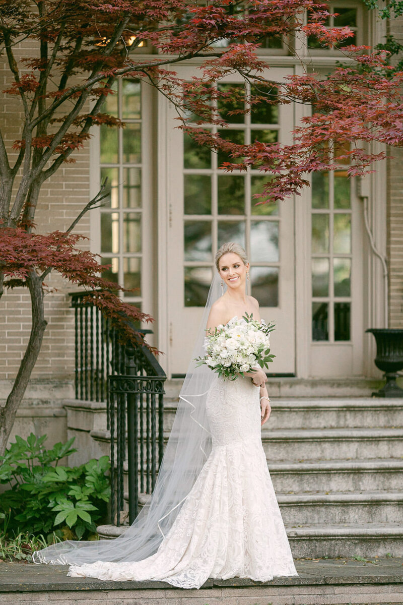 Bride in grey ruffled ball gown smiling and running in green garden