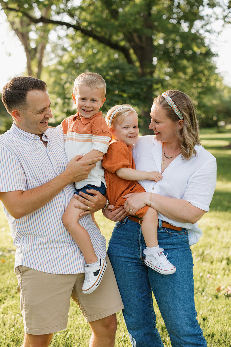 Blonde mom holding daughter with brunette father holding blonde son.