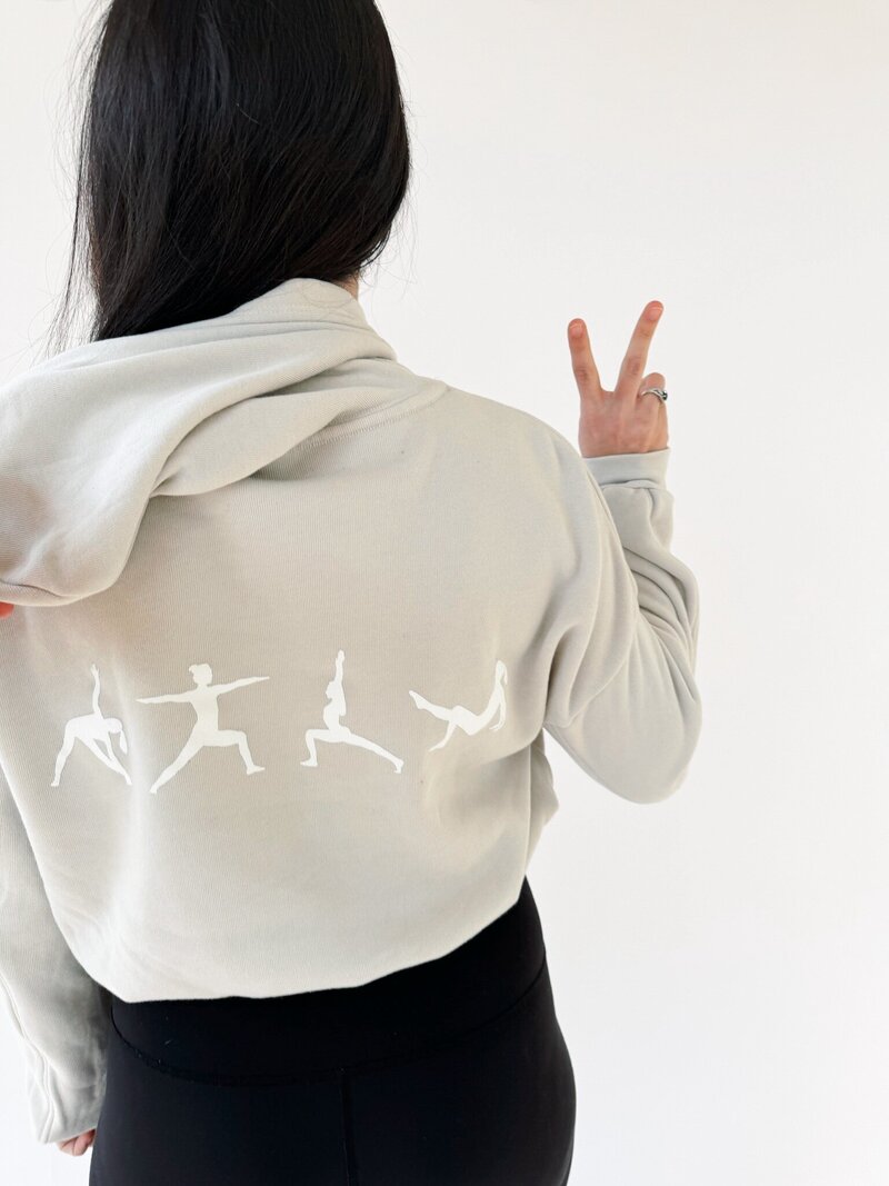 back of woman wearing oat colored hoodie with white icons on the back