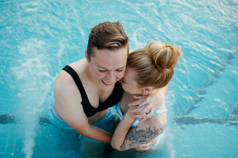A couple hugging and standing in a pool.