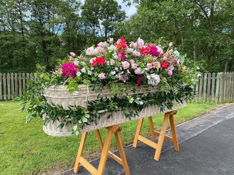 Wicker casket with flowers and a garland