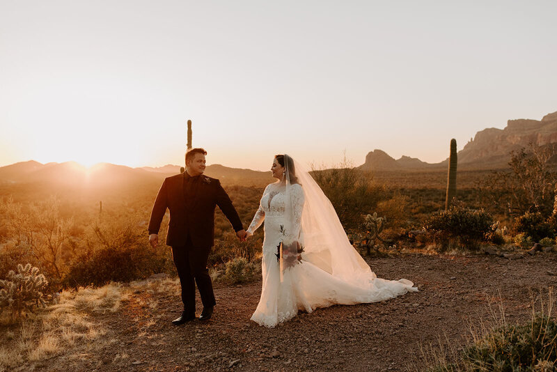 bride and groom holding hands in desert