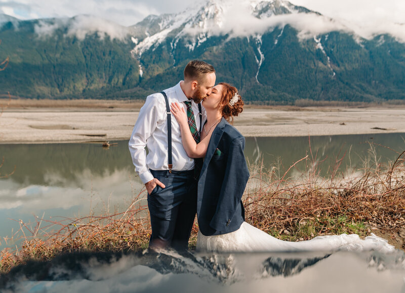 Mountains in the background at Fraser River Lodge. Wedding couple kissing closely on their wedding day.