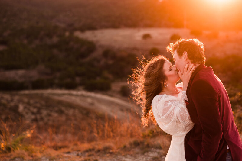 Couple kiss on top of the hills during their engagement  session in Austin, Texas. Photo taken by Austin Engagement Photographers, Joanna & Brett Photography