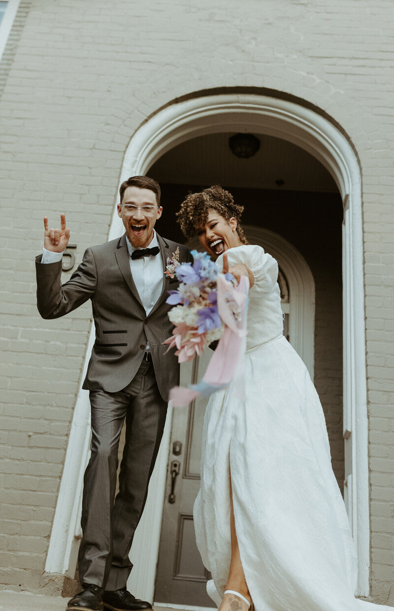 Couple standing on the steps of a gray building.