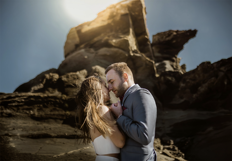 Engagement photo session. of a German couple who is hugging in front of a rock in Iceland