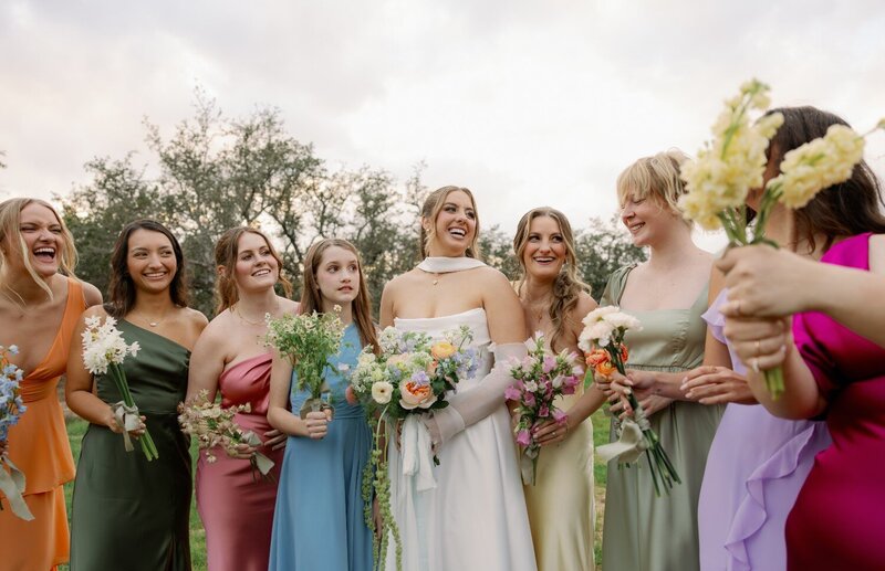 Bridal party in bright, colorful dresses posing together outdoors in Maine