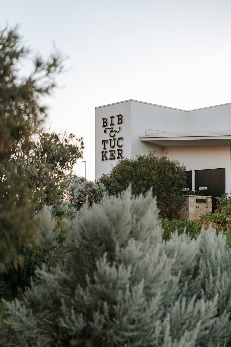 The facade of Bib and Tucker restaurant with trees in the foreground