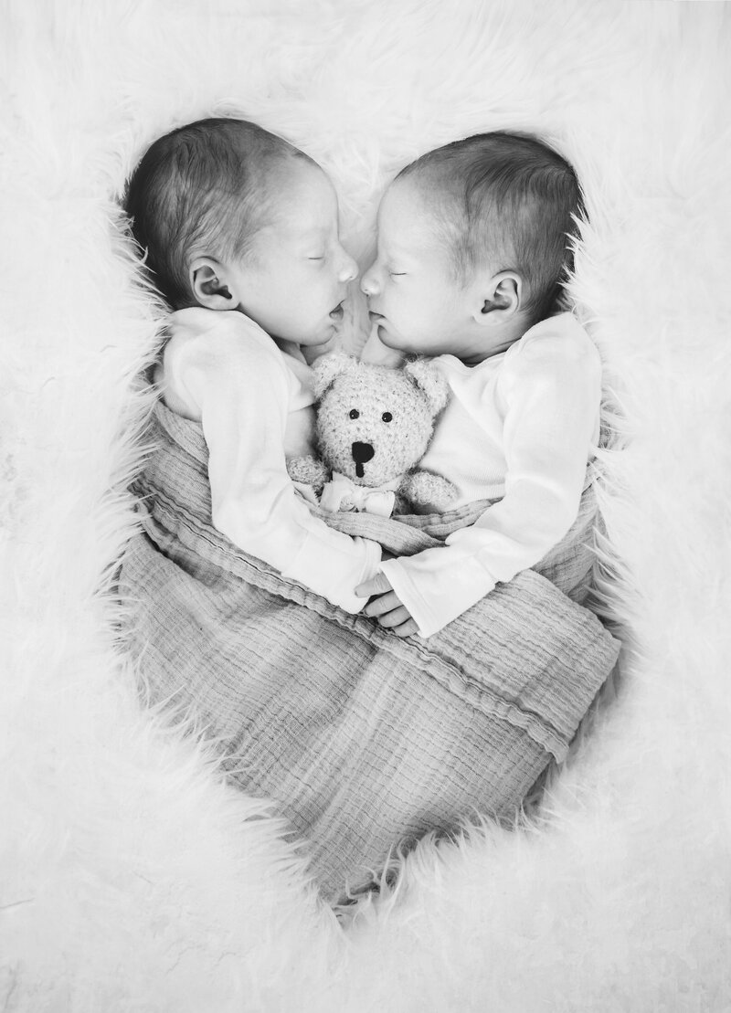 newborn twins cuddling for photos at studio in Hamilton, New Jersey.