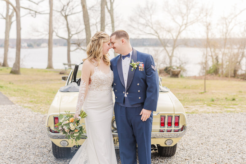 Newlyweds lean against a yellow vintage Ford Mustang parked by a lake taken by a Grand Rapids Wedding Photographer