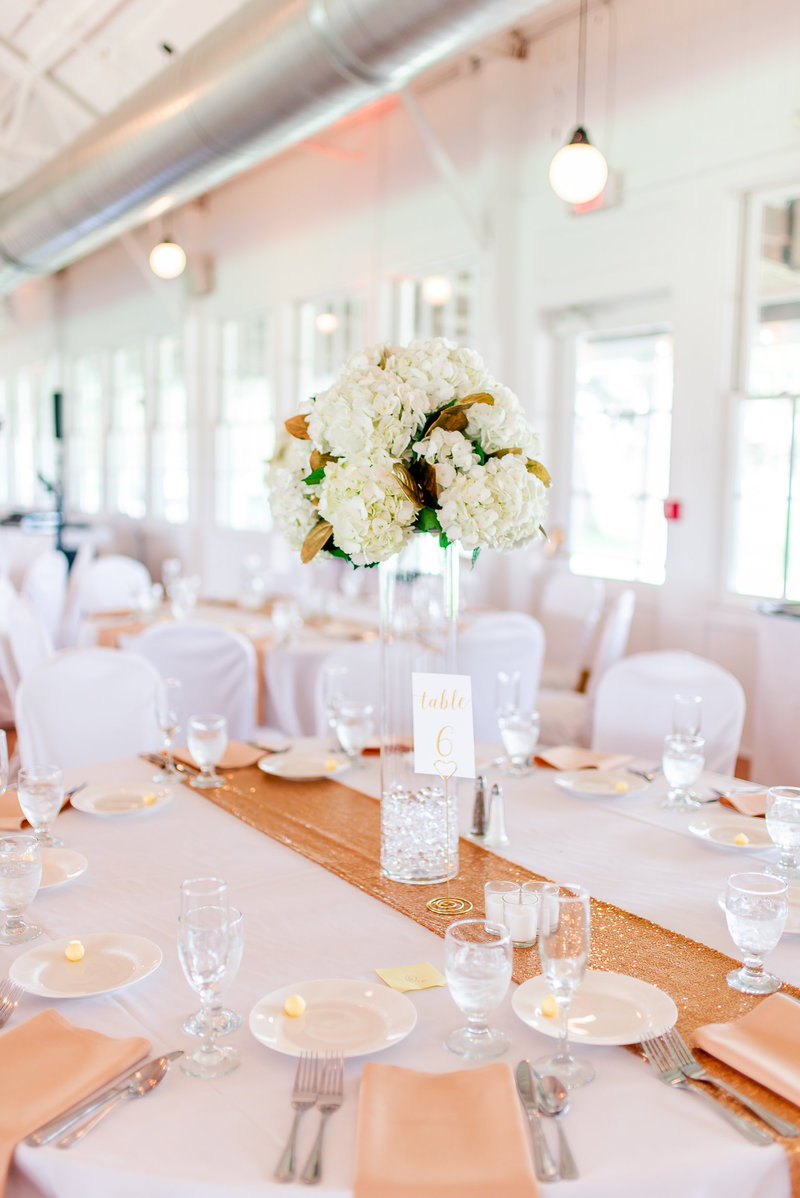 White floral centerpieces in a white reception room with gold accents