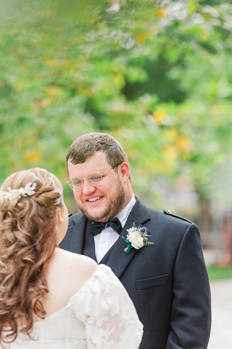 Scottish groom smiling at jewish bride with her back to the camera outside in Navy Yard DC 