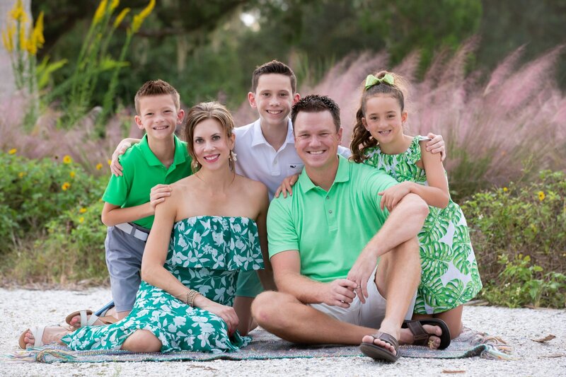 A family of five in coordinating green outfits  at Phillippi Estate Park in Sarasota, Fl.