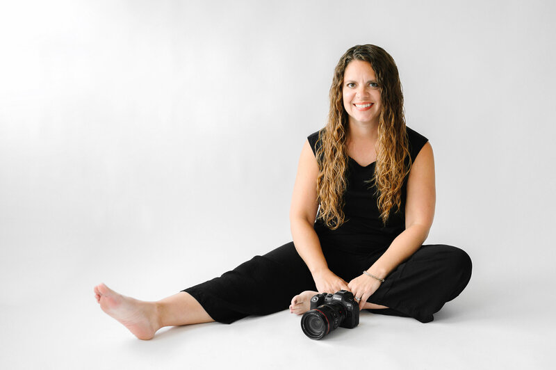 Photographer Janelle Reule working on her laptop with her camera and coffee next to her. 