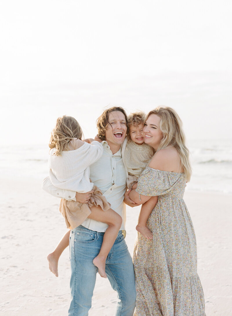 Family of 4 laughing on the beach