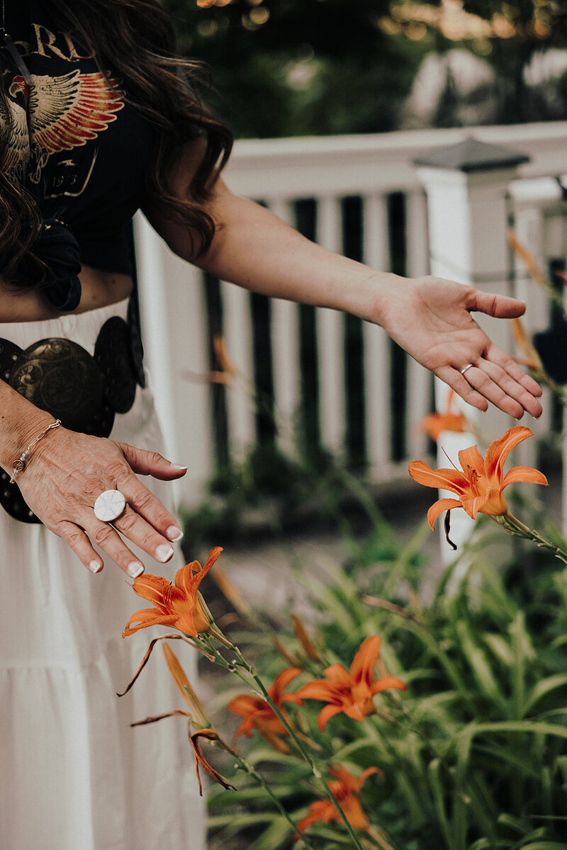 a woman with her hands outstretched over orange flowers 