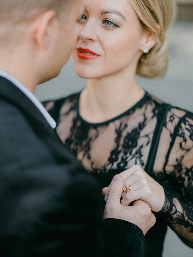 Woman in black dress looking  into her husbands eyes and smilng while holding his hand