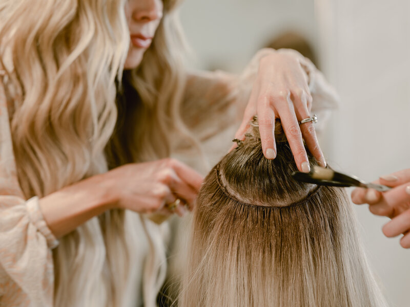 Hairstylist creating seamless and invisible hand tied hair extensions