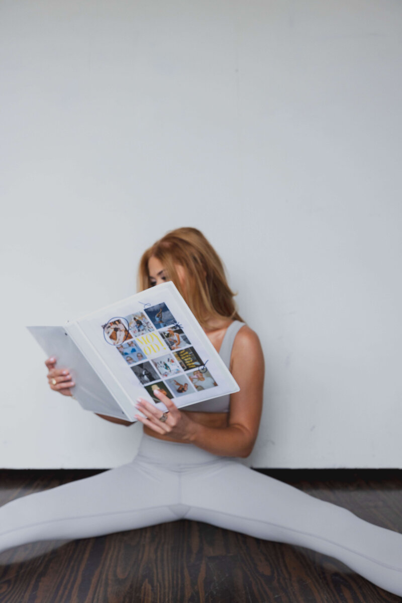ALT: Grace sitting on floor looking at binder of client projects