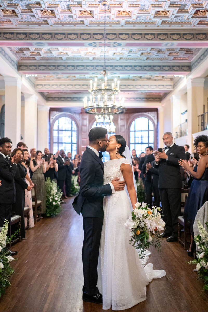 Bride and groom embrace and kiss as they've walked back down the aisle after being married