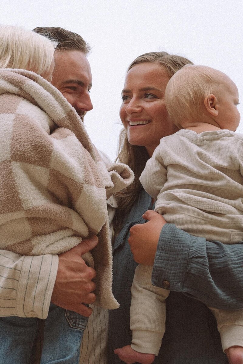 mother and father snuggling children at crescent bay beach