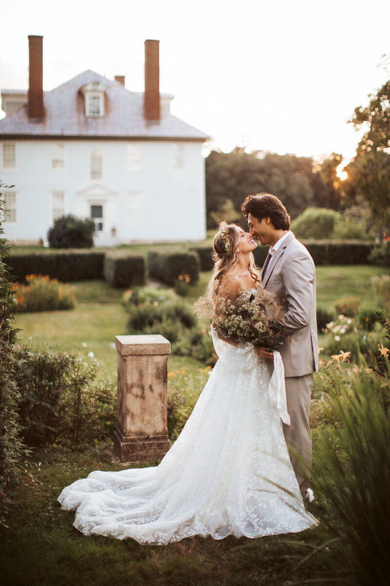 Bride and groom embracing in the garden at sunset outside a historic estate during their Portland Maine wedding.