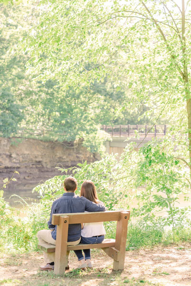 Couple sits on a bench on the riverside.