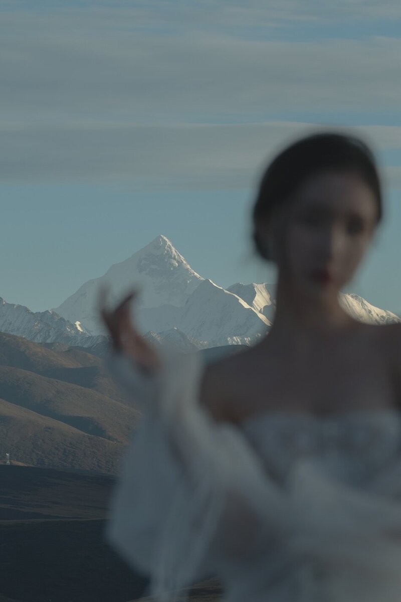 A beautiful woman wearing a couture bridal dress photographed in wild fields with snow capped mountains in the background.