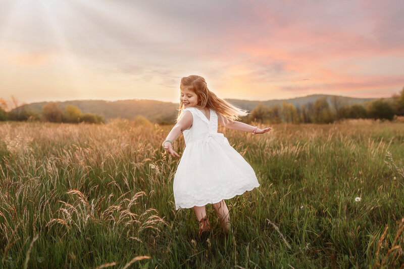 Little girl twirls in a beautiful field on the Blue Ridge Parkway outside of Asheville, NC.