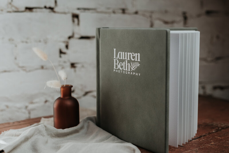 Green Fine Art Wedding Album displayed on a wooden table with dried flowers | Folio Albums