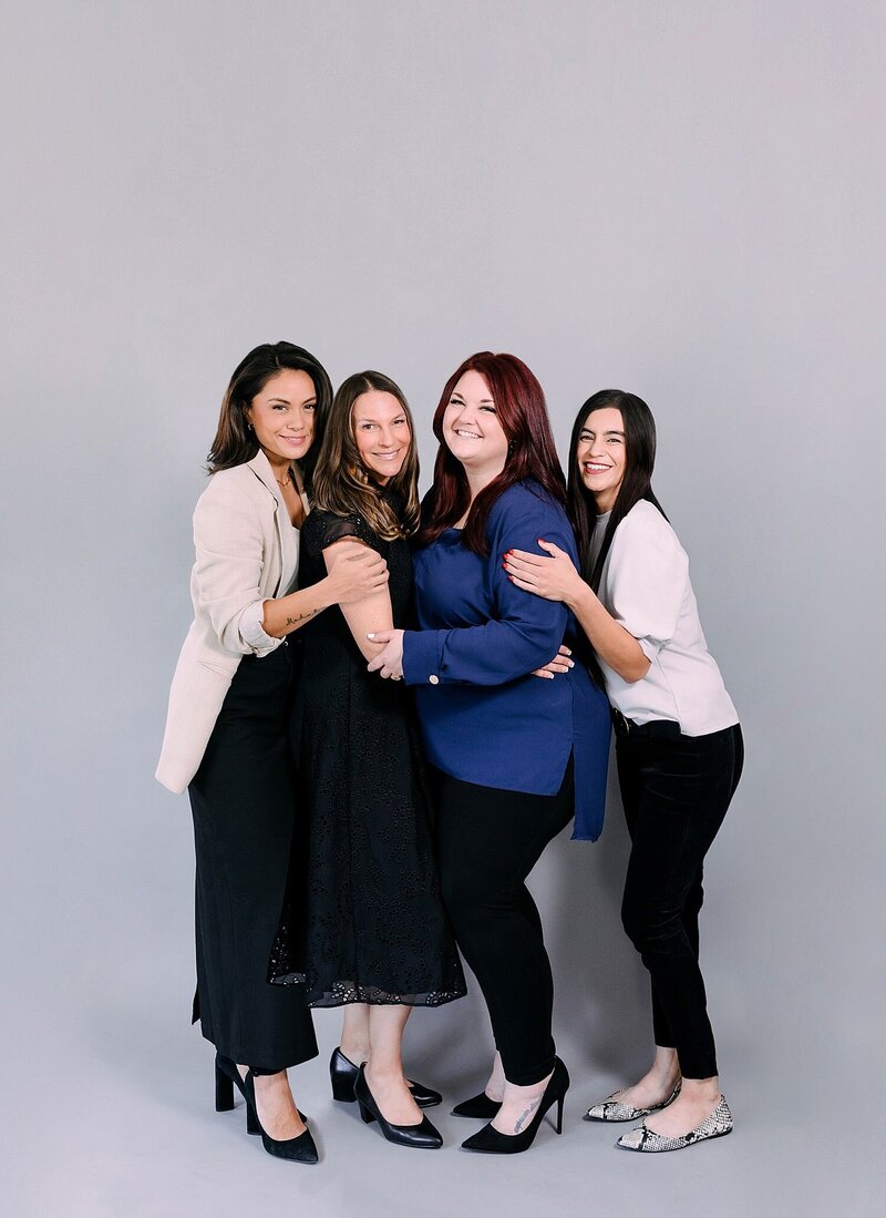 4 women in wedding photography team embrace