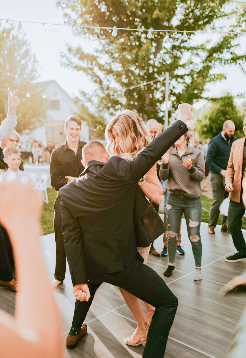 A groom getting krunk with his wife at their outdoor dance party. I mean, his fist is up and he's really getting low. He's nailing this.