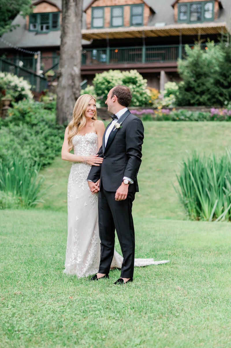 Husband and wife hold hands and smile at each other outside of Deer Mountain Inn