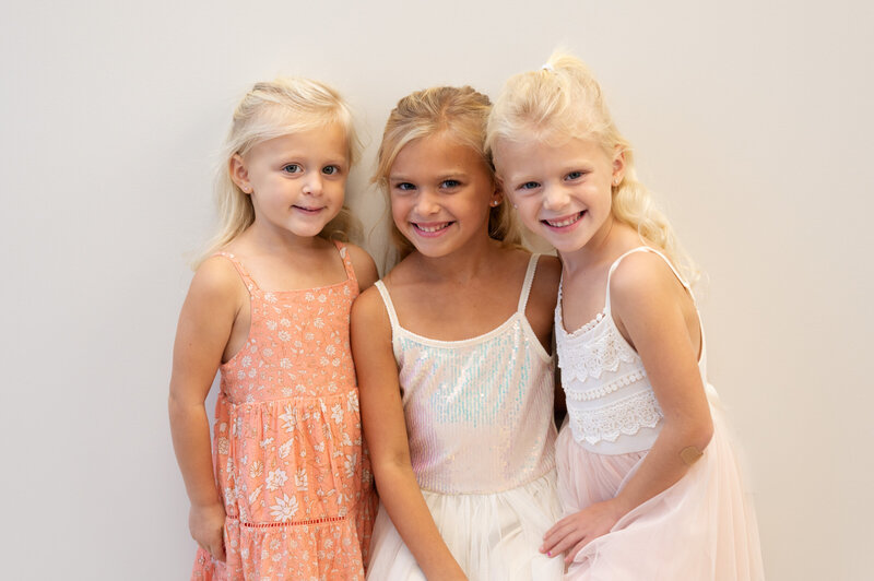three sisters in studio wearing pink, peach and cream