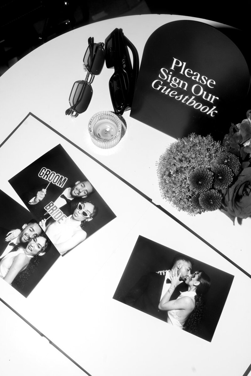 Wedding guestbook table with printed photo booth photos from Always Present, inviting guests to sign.