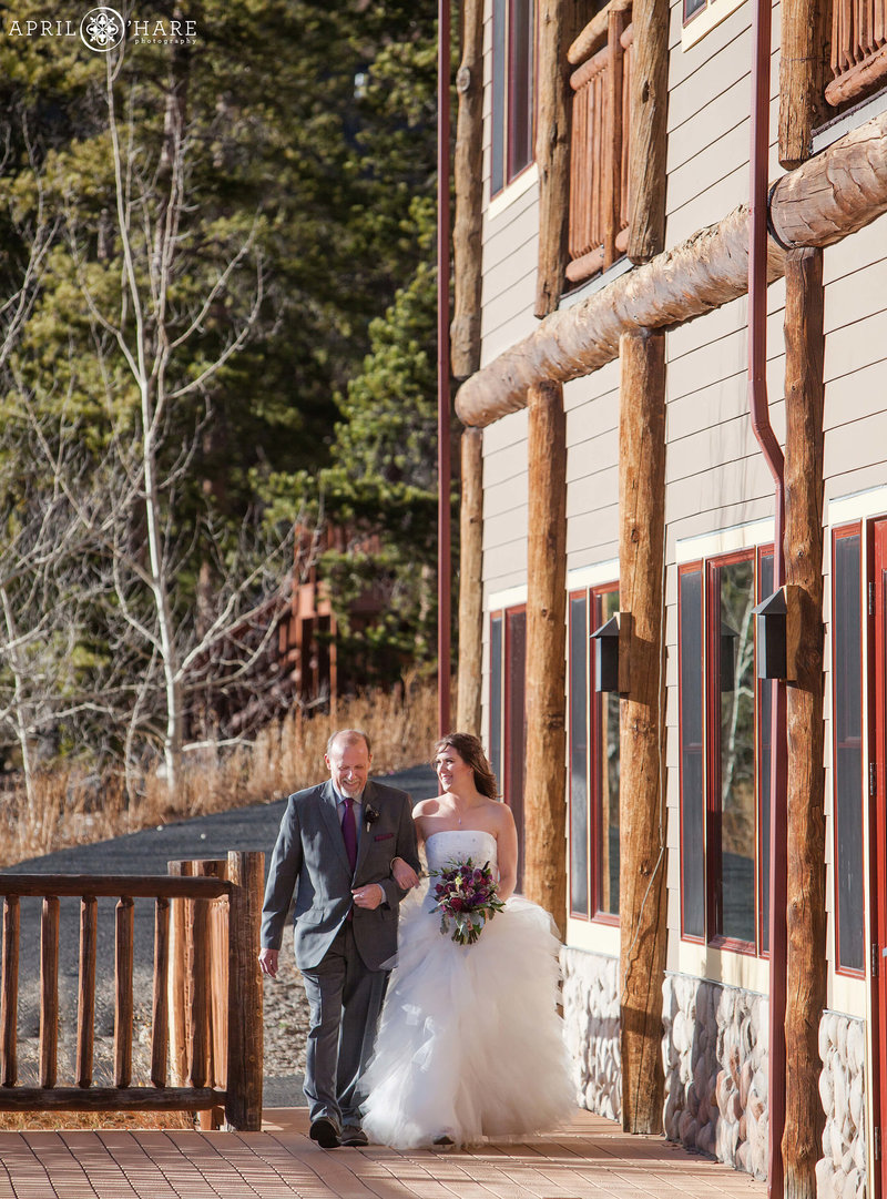 Bride walks down the aisle at her outdoor wedding on the Skyview Deck at Lodge at Breckenridge in Colorado
