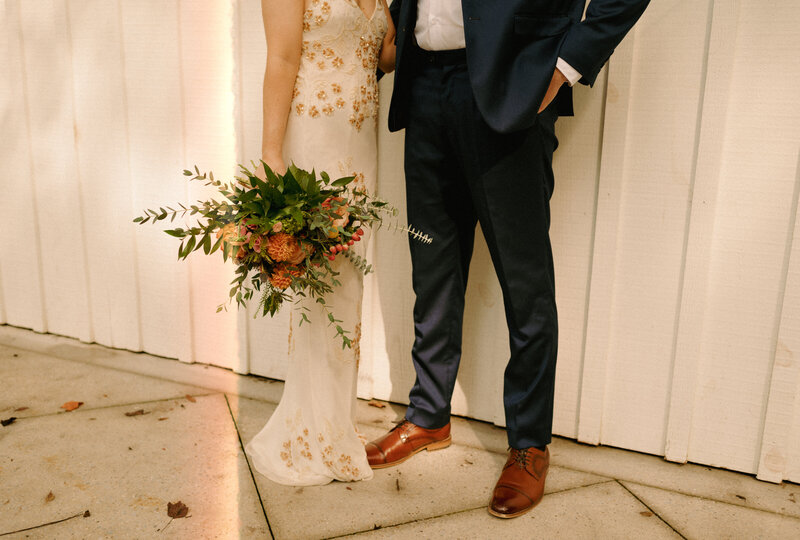 A bride and groom detail photo of their outfits and florals.